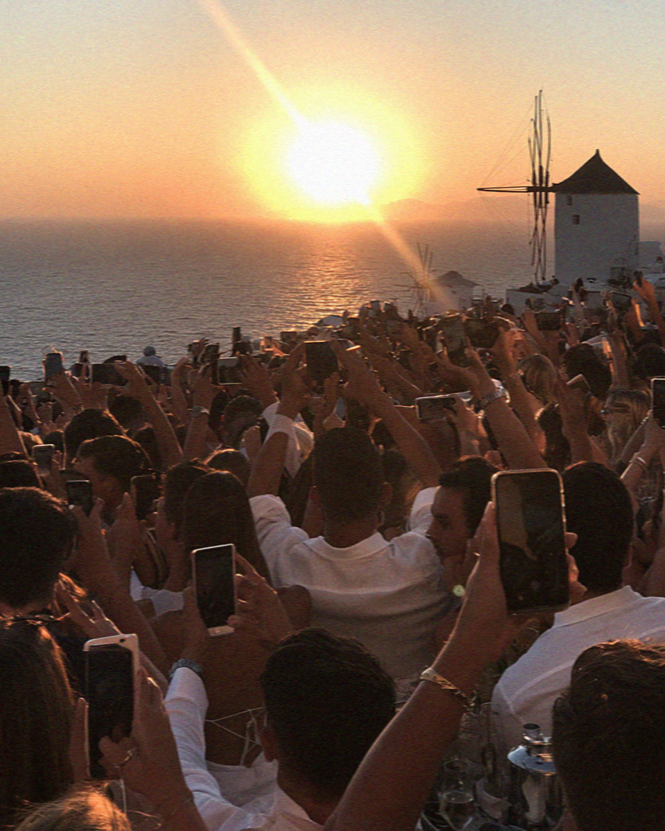 Phones raised into the sun for the sunset at Oia in Santorini