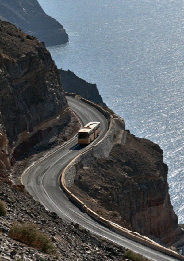 The switchback road climbing the caldera wall in Santorini with a bus on the bend