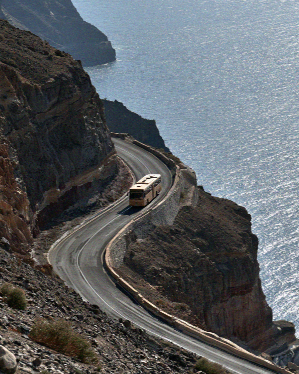 The switchback road climbing the caldera wall in Santorini with a bus on the bend