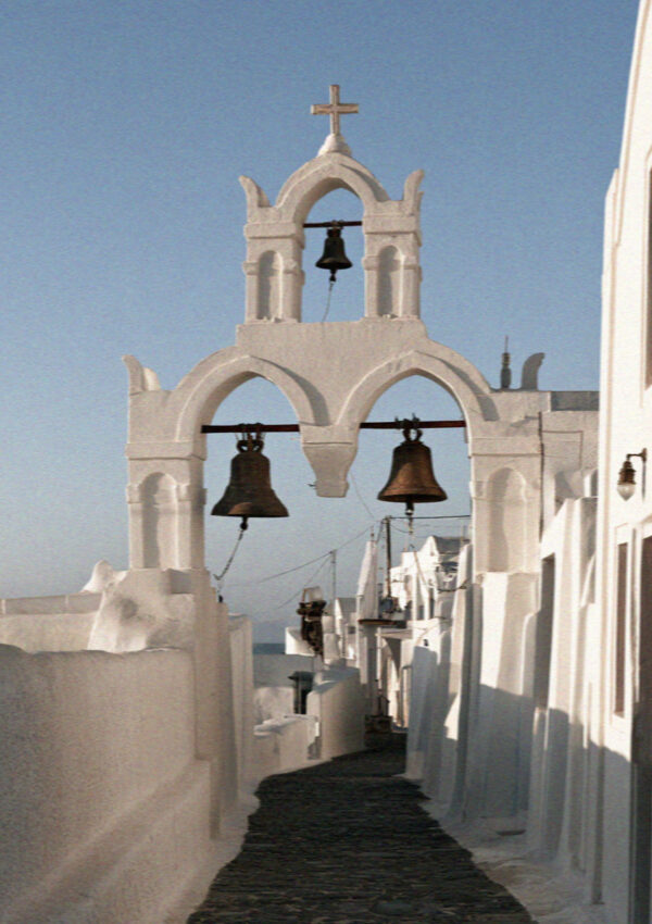 A whitewashed bell tower with bronze bells above a lane in Megalochori, Santorini