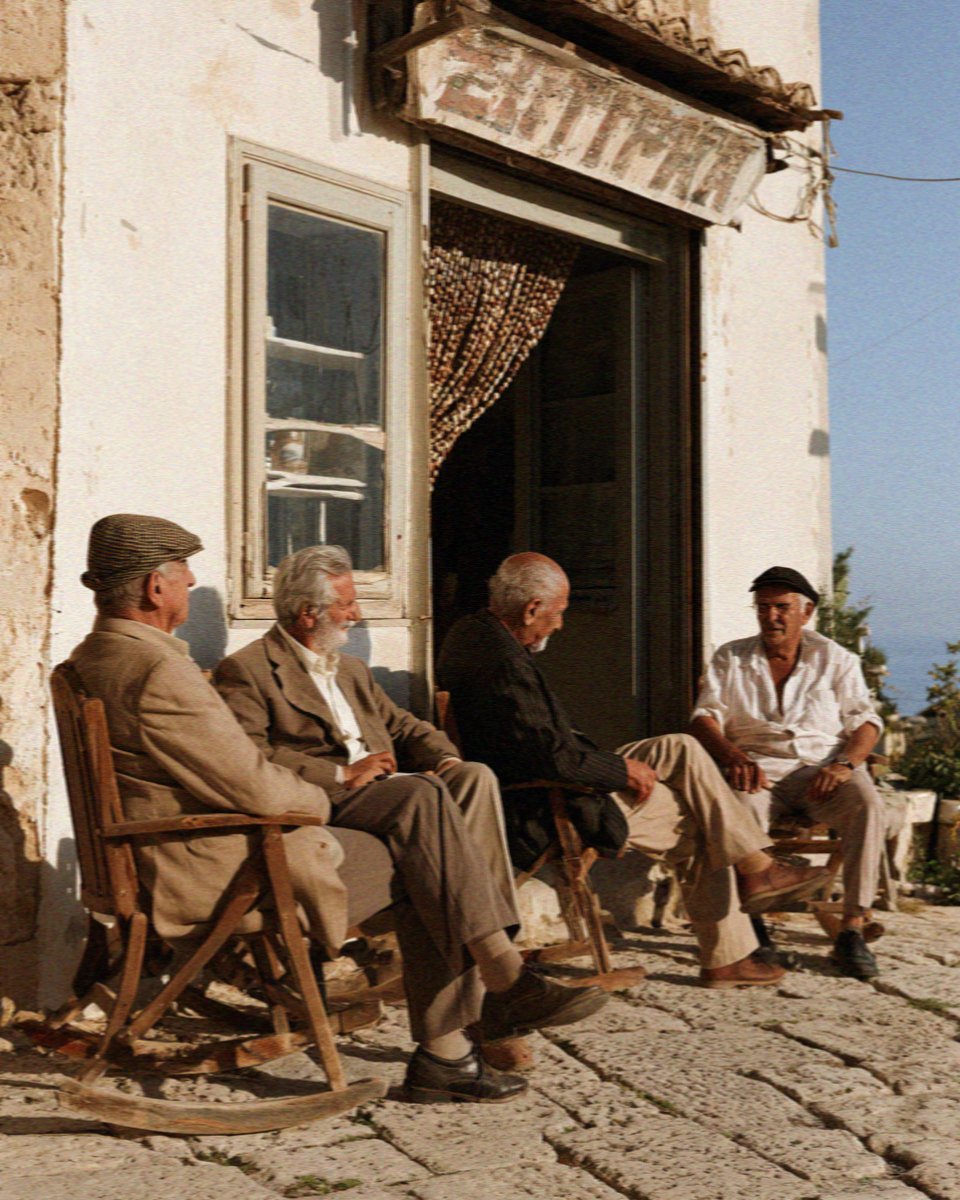 Four older men sitting outside the bar in the courtyard at Scopello, west of Palermo in Sicily