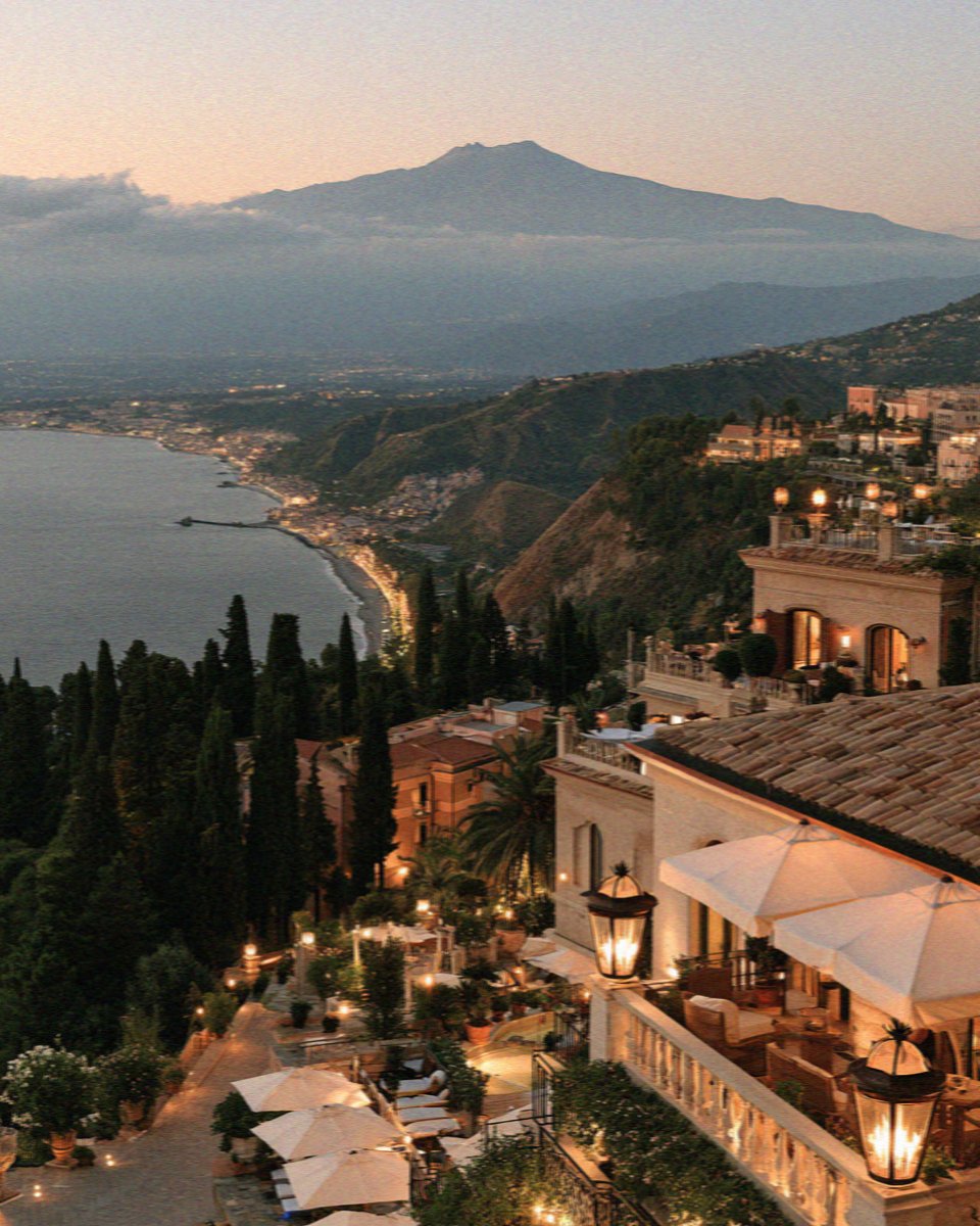 Mount Etna seen over the rooftops of Taormina in Sicily at dusk