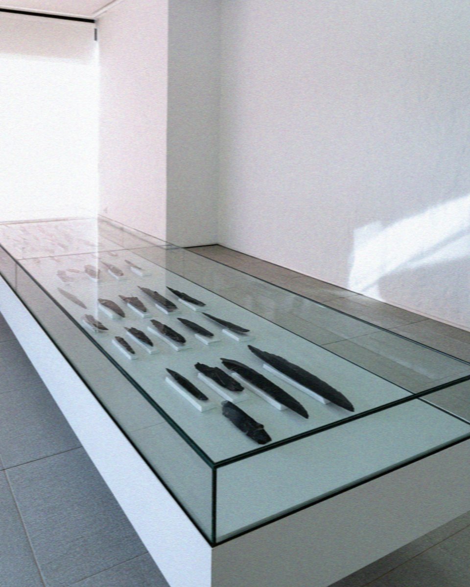 Obsidian blades displayed in a glass case at the mining museum in Adamas, Milos