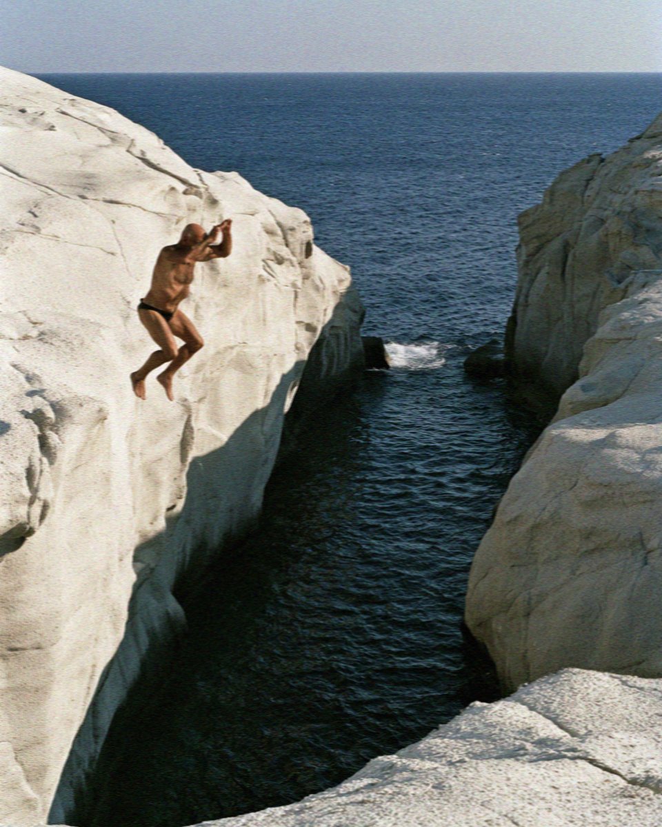 A swimmer jumping from the white rock into the channel at Sarakiniko on Milos