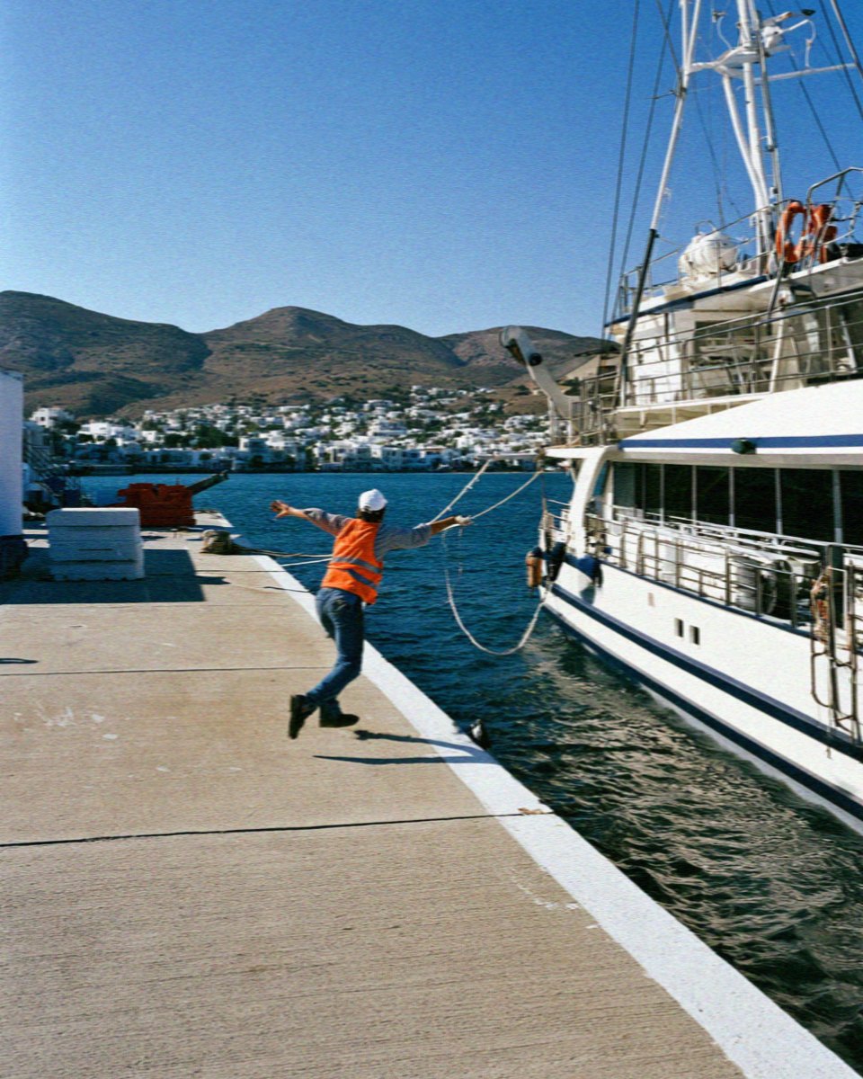 A deckhand throwing a line as the boat docks at Adamas on Milos