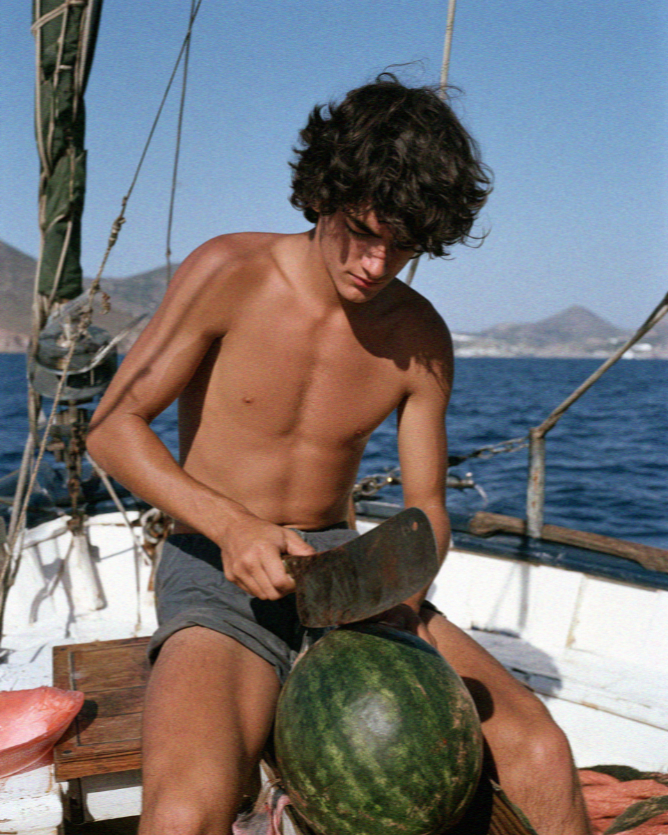 The deckhand cutting a watermelon on deck off Milos
