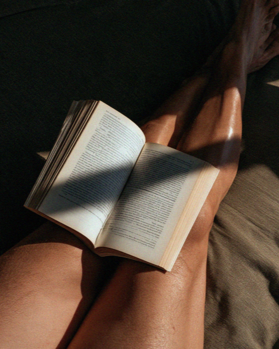 An open book across a lap in hard Mykonos sunlight