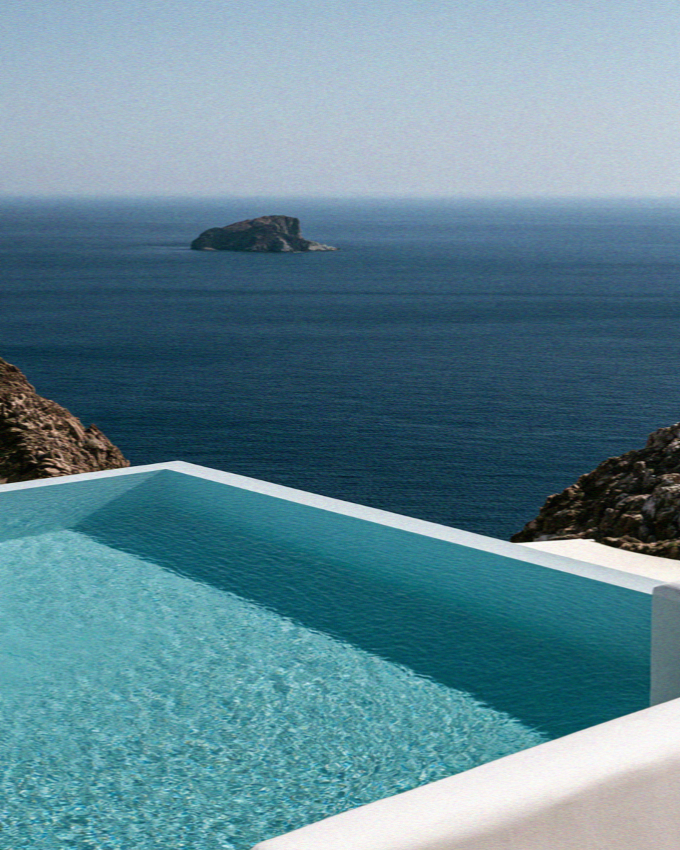 A villa infinity pool above the sea with a small island offshore on Mykonos