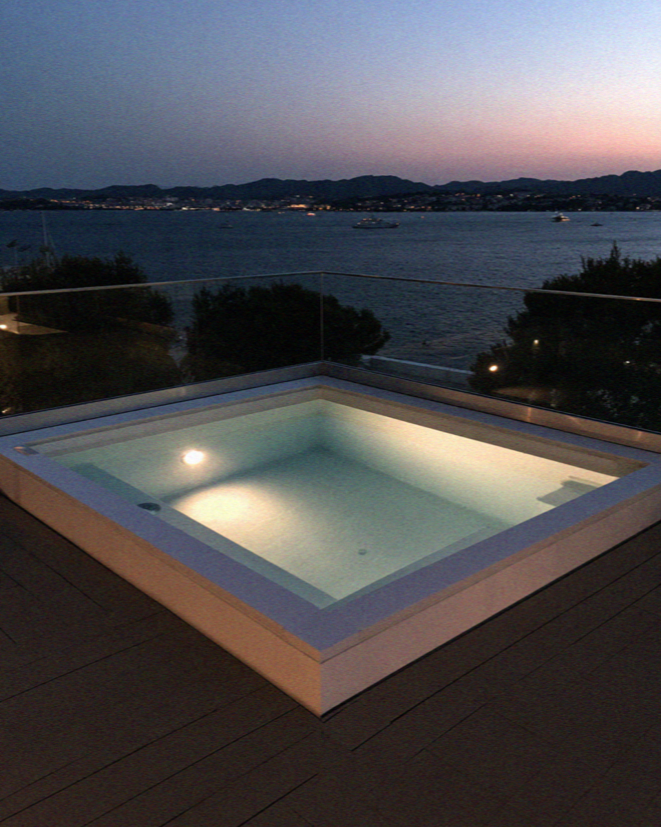A lit hot tub on a villa terrace above the bay at dusk on Mykonos