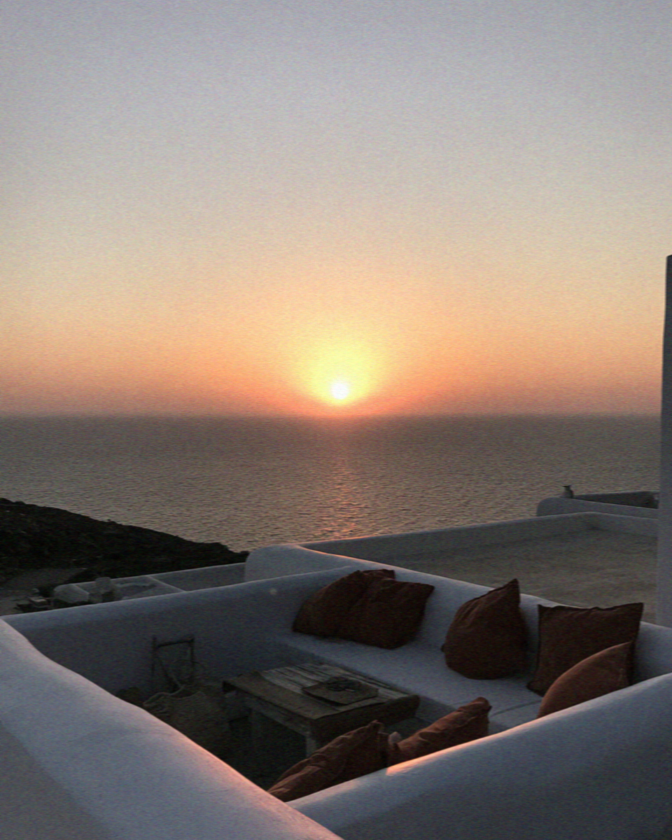 The sun sitting on the horizon over the sea seen from a villa terrace on Mykonos