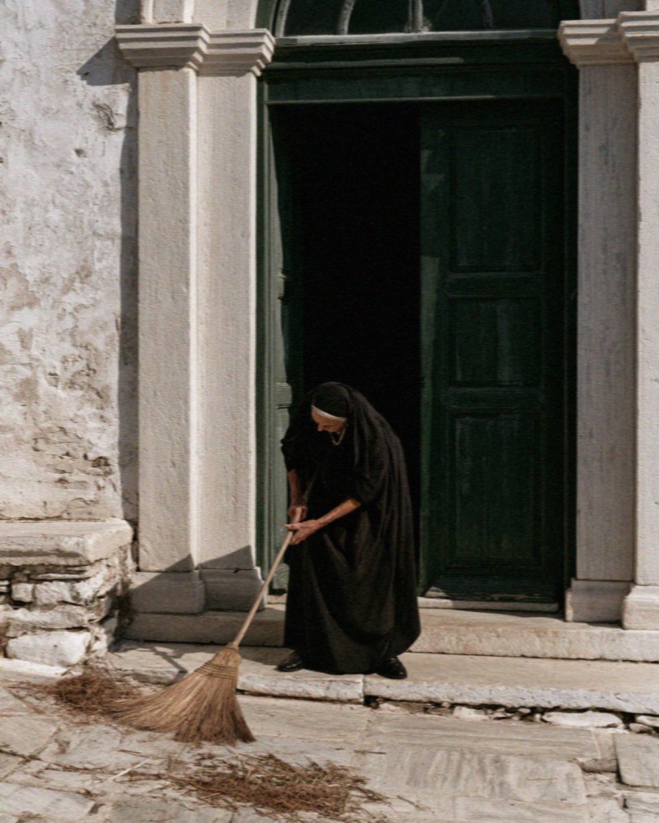 A nun sweeping beside a church door in the courtyard of the Panagia Ekatontapyliani in Parikia, Paros