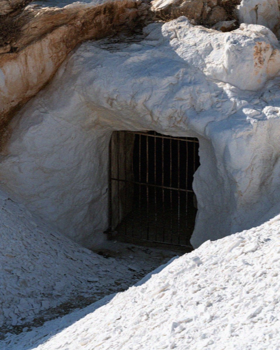 An ancient marble quarry entrance behind an iron grille at Marathi on Paros