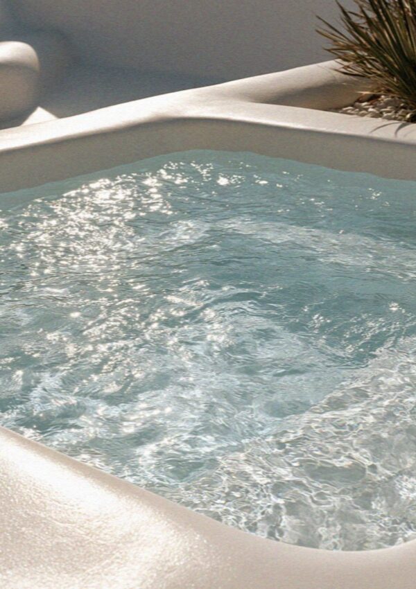 A small plunge pool glittering in the afternoon light on a whitewashed terrace on Santorini