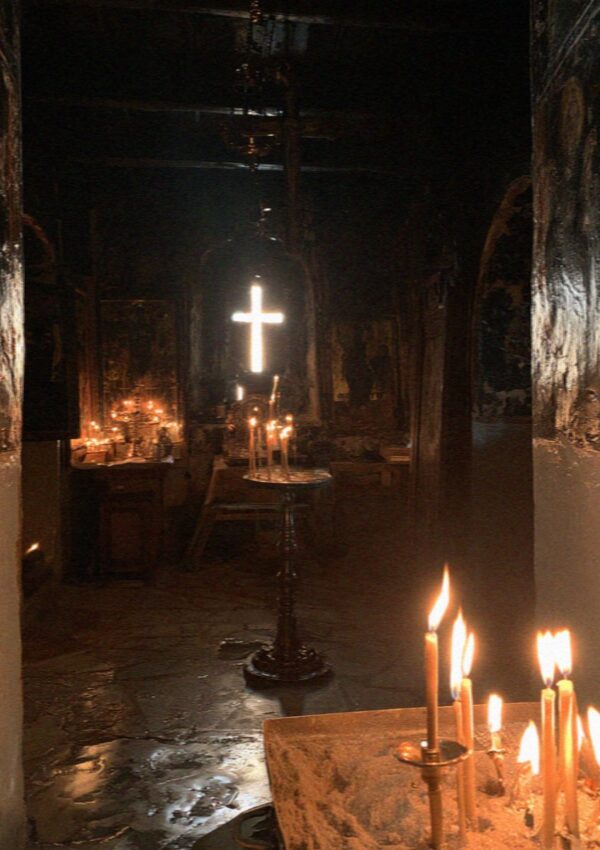 Candles burning in the dark interior of an old church in Pyrgos on Santorini