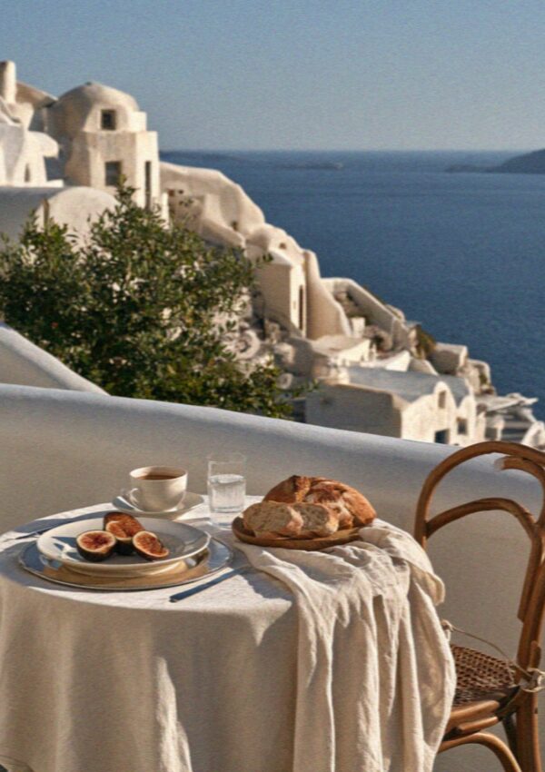 Figs, bread and coffee on a linen-covered table on a whitewashed terrace above the sea on Santorini