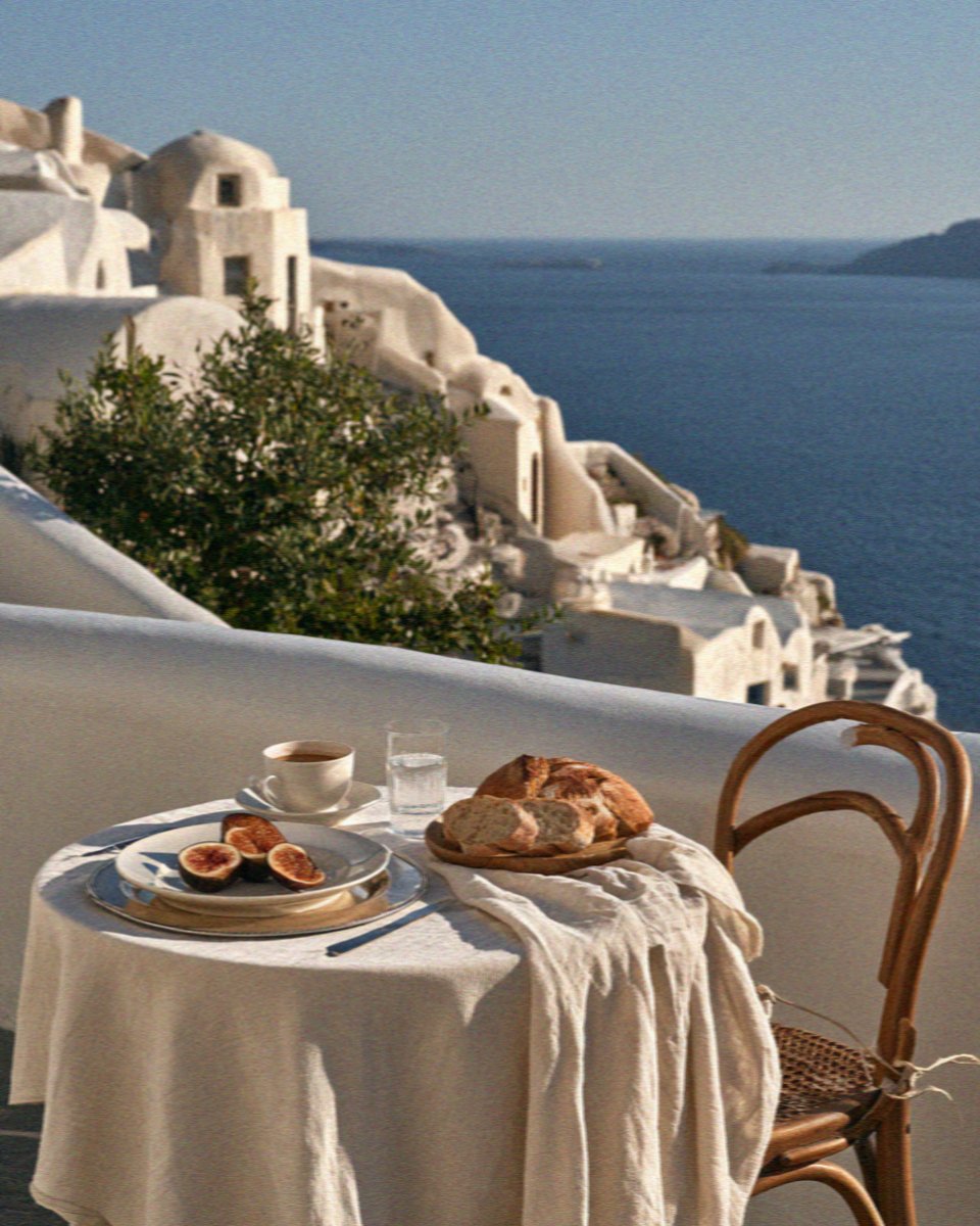 Figs, bread and coffee on a linen-covered table on a whitewashed terrace above the sea on Santorini
