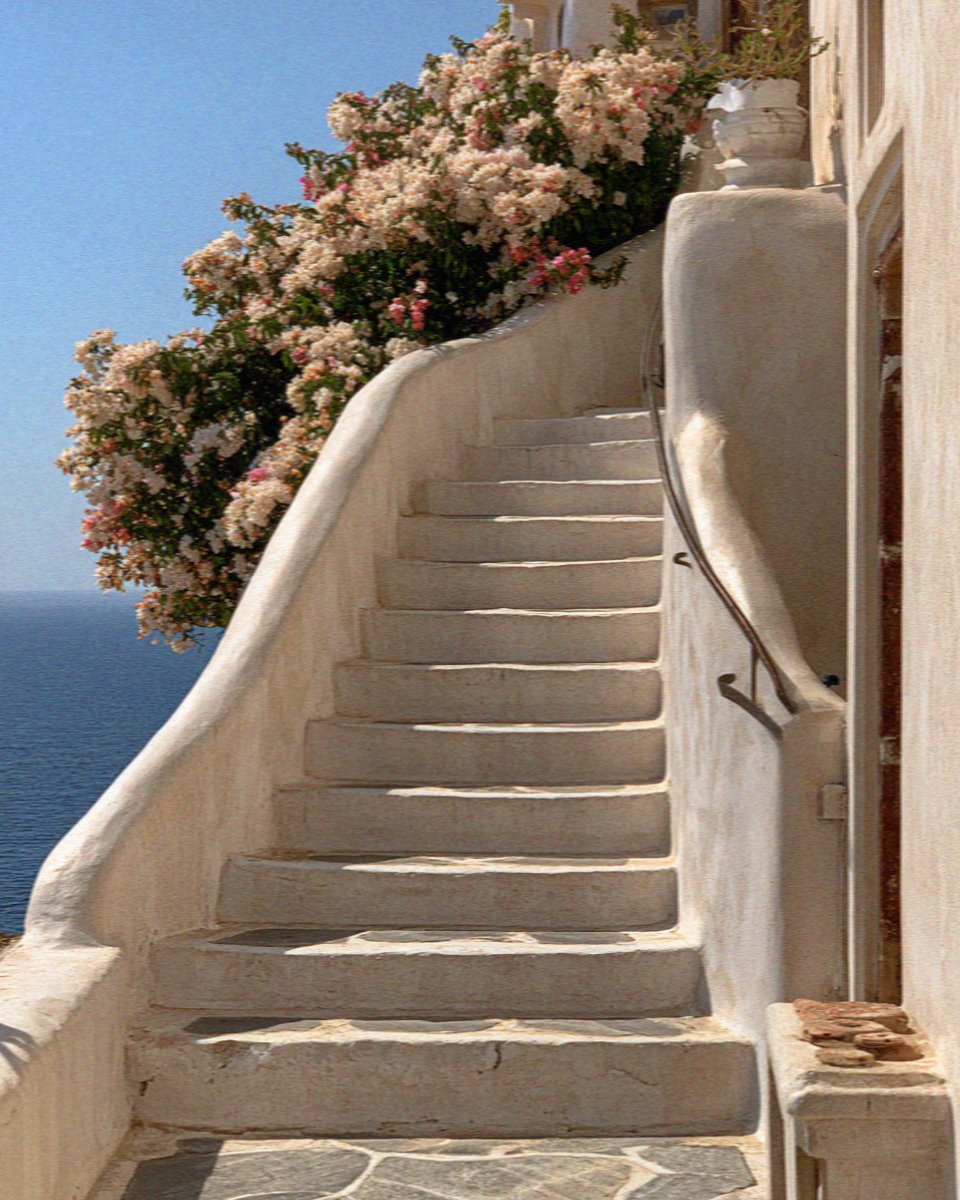 Whitewashed steps curving up beside a flowering bougainvillea on Santorini
