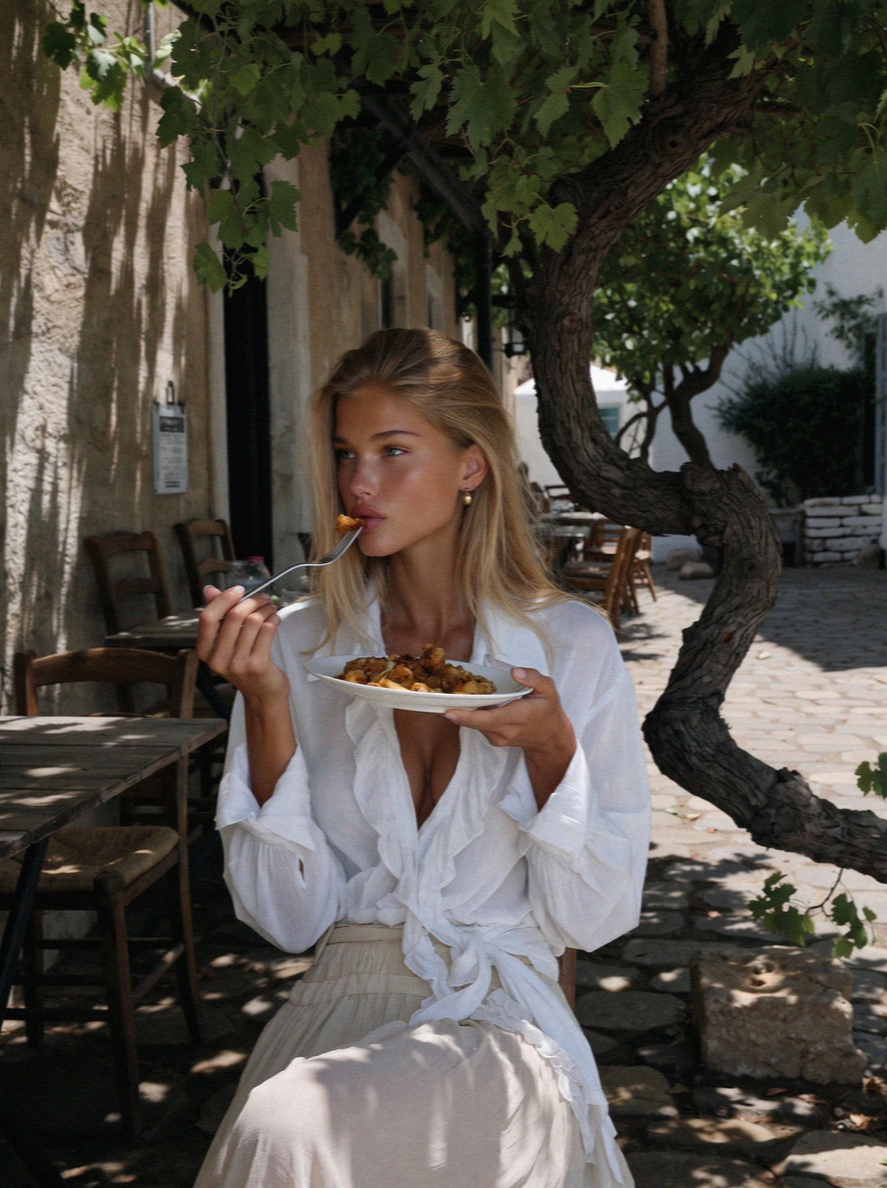 Victoria van der Berg eating a plate of Naxos potatoes at a table under a vine